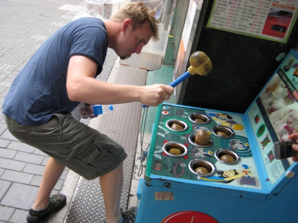 Man hitting whack-a-mole machine with a mallet